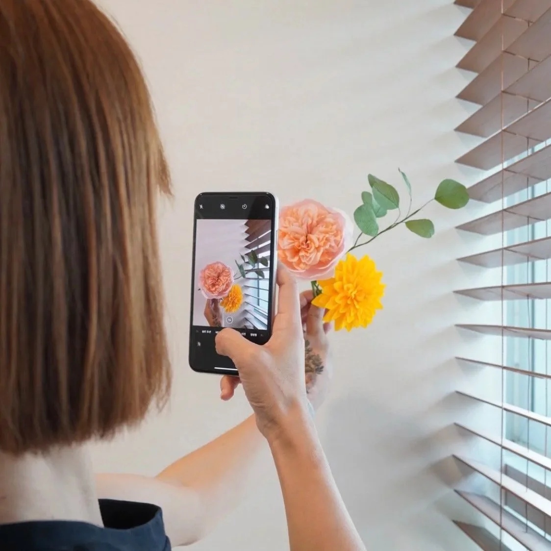 Merremade student taking a photo of a handmade paper dahlia flower arrangement during in-person workshop in Seoul Korea.