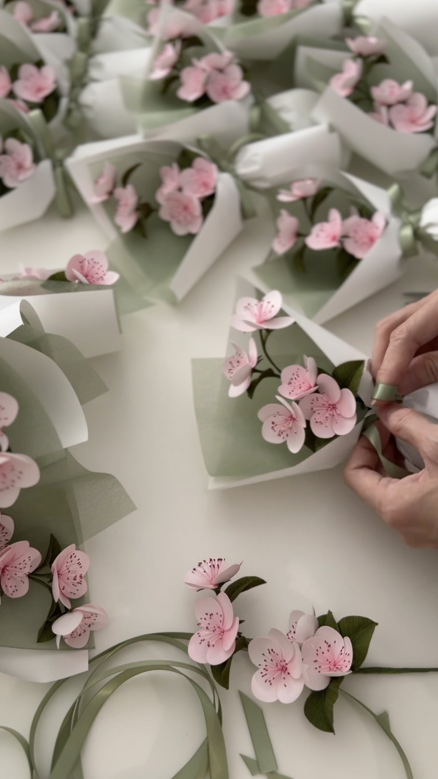 Merremade arranging pink paper cherry blossom flowers with green leaves bouquets for Van Cleef & Arpels Singapore event.