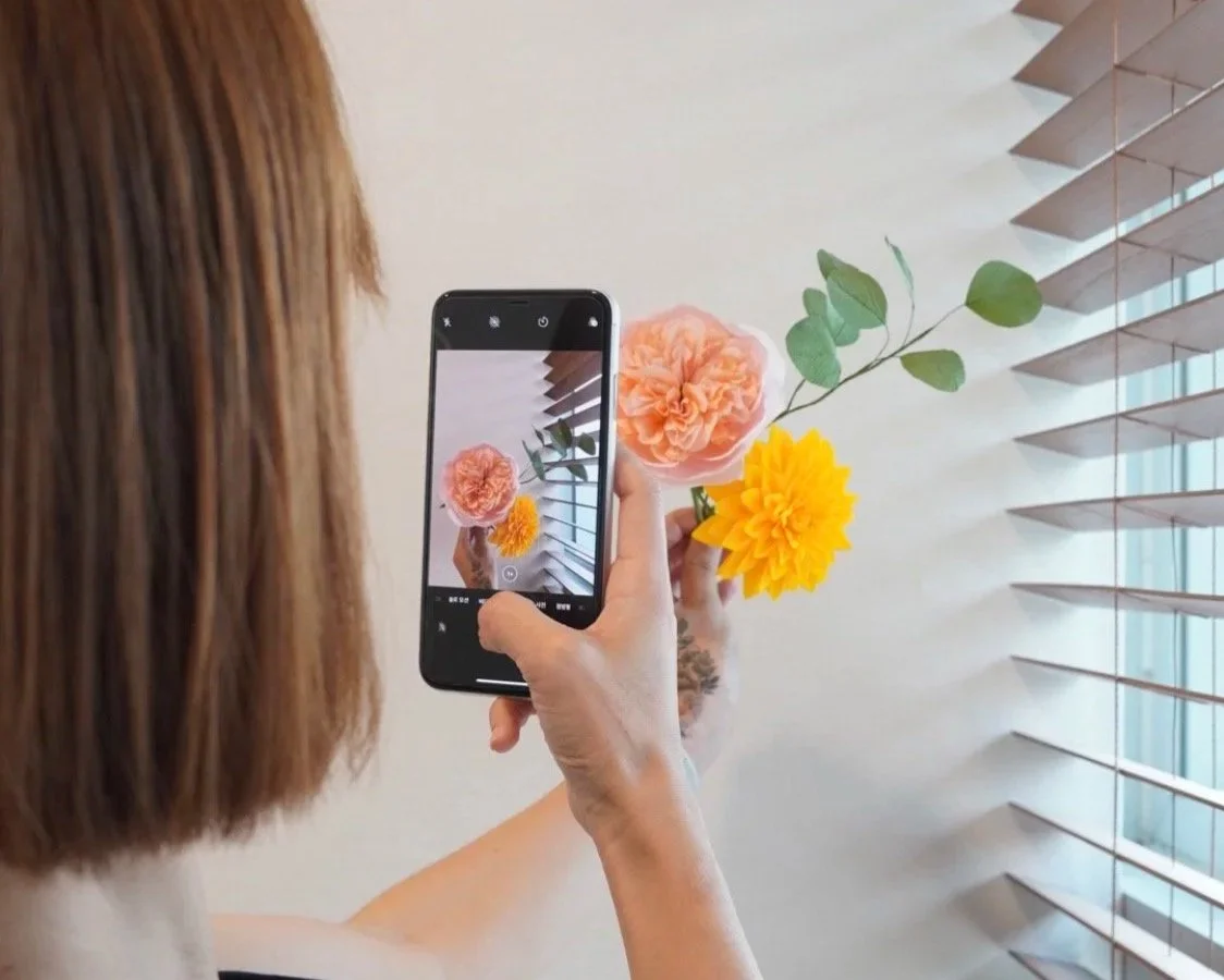 Merremade student taking photo of her well made paper flowers.