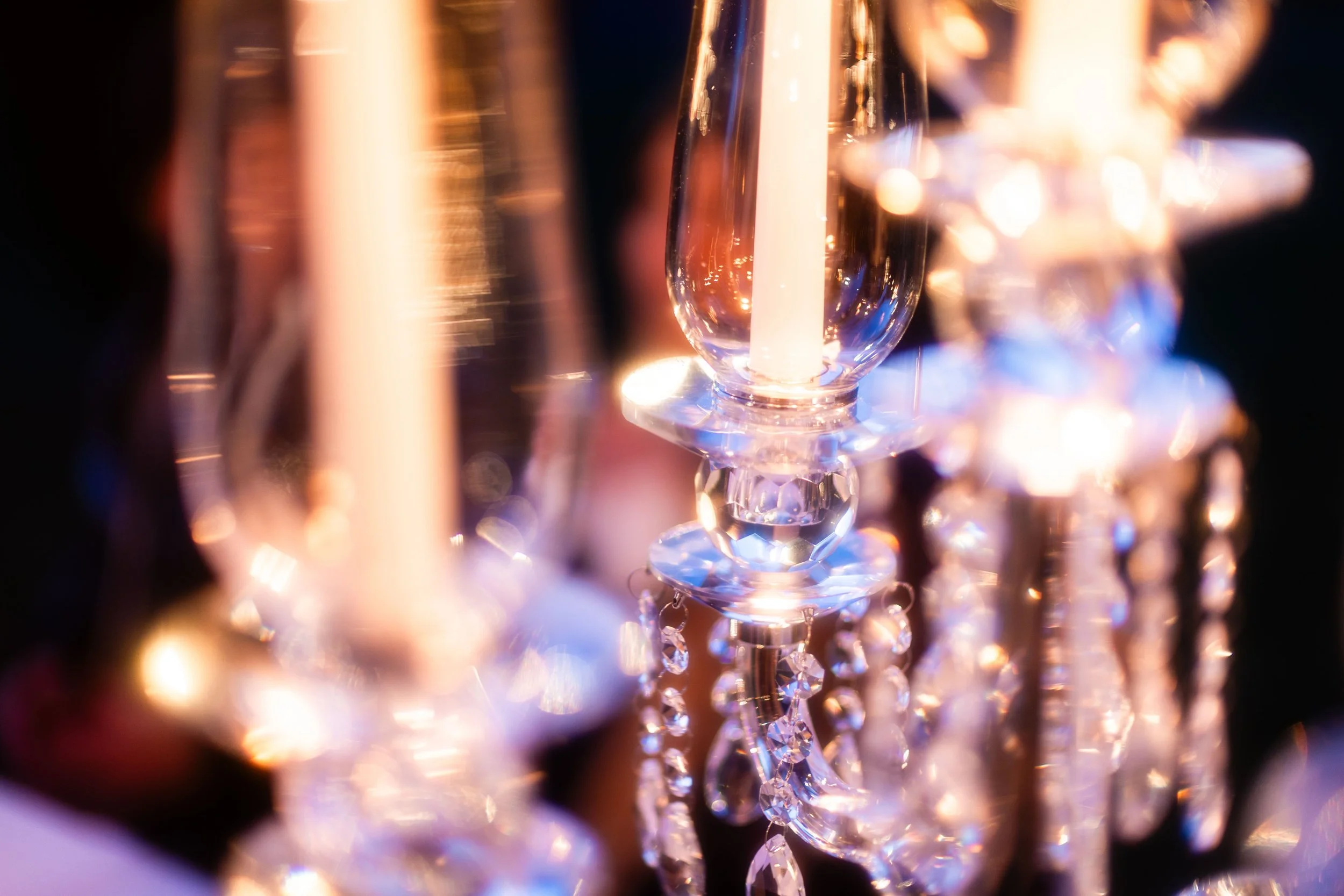 Calici di cristallo con candele accese e decorazioni luminose.