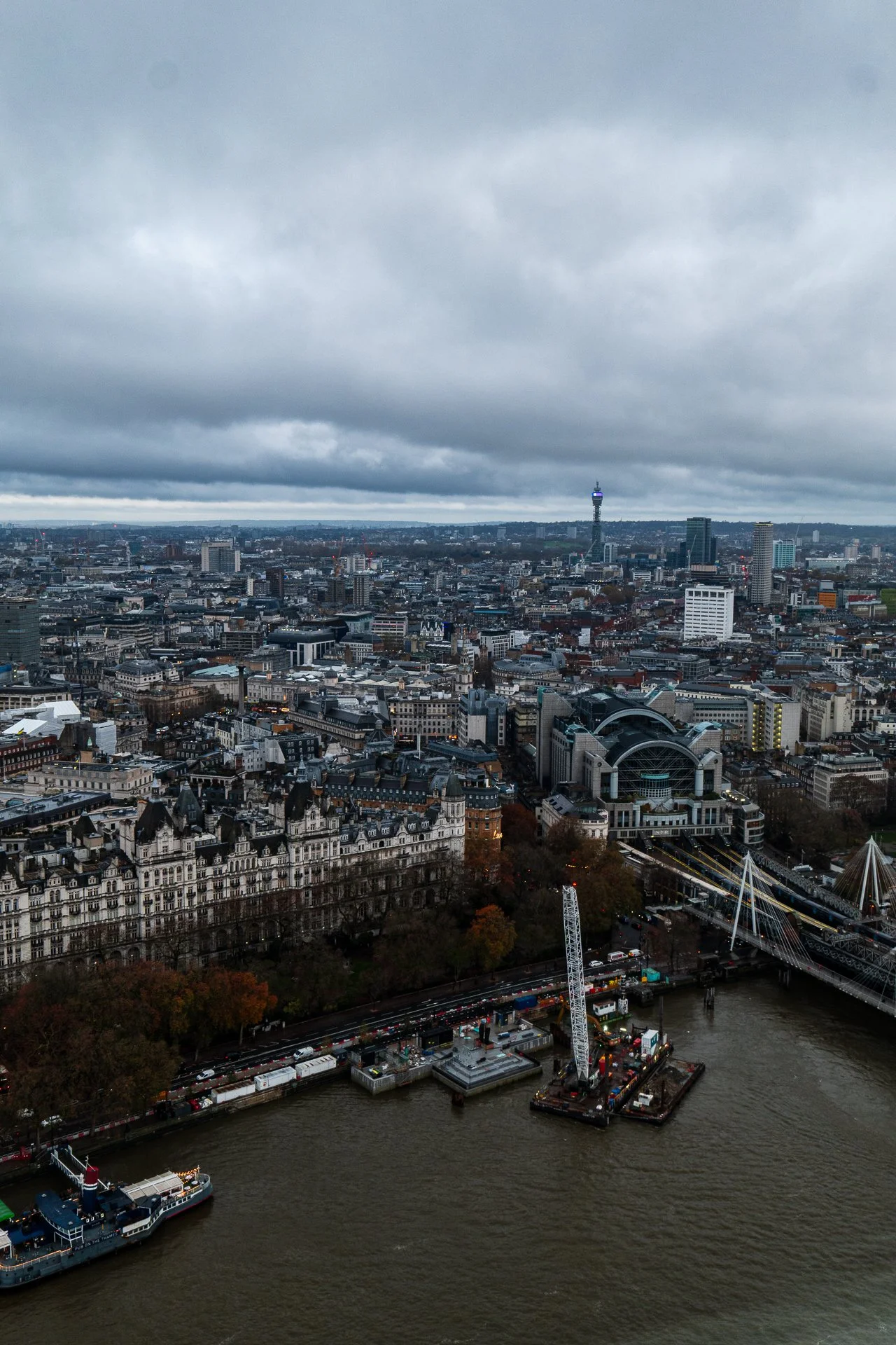 Aerial view of London cityscape with the River Thames, buildings, and cloudy sky.
