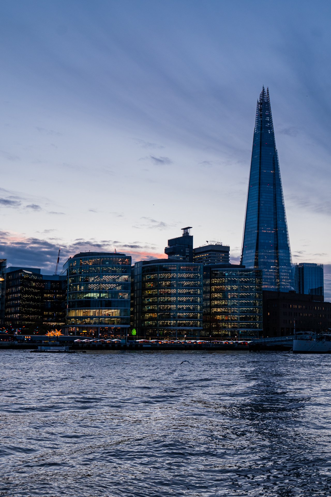 The Shard and modern buildings by the River Thames at sunset in London.