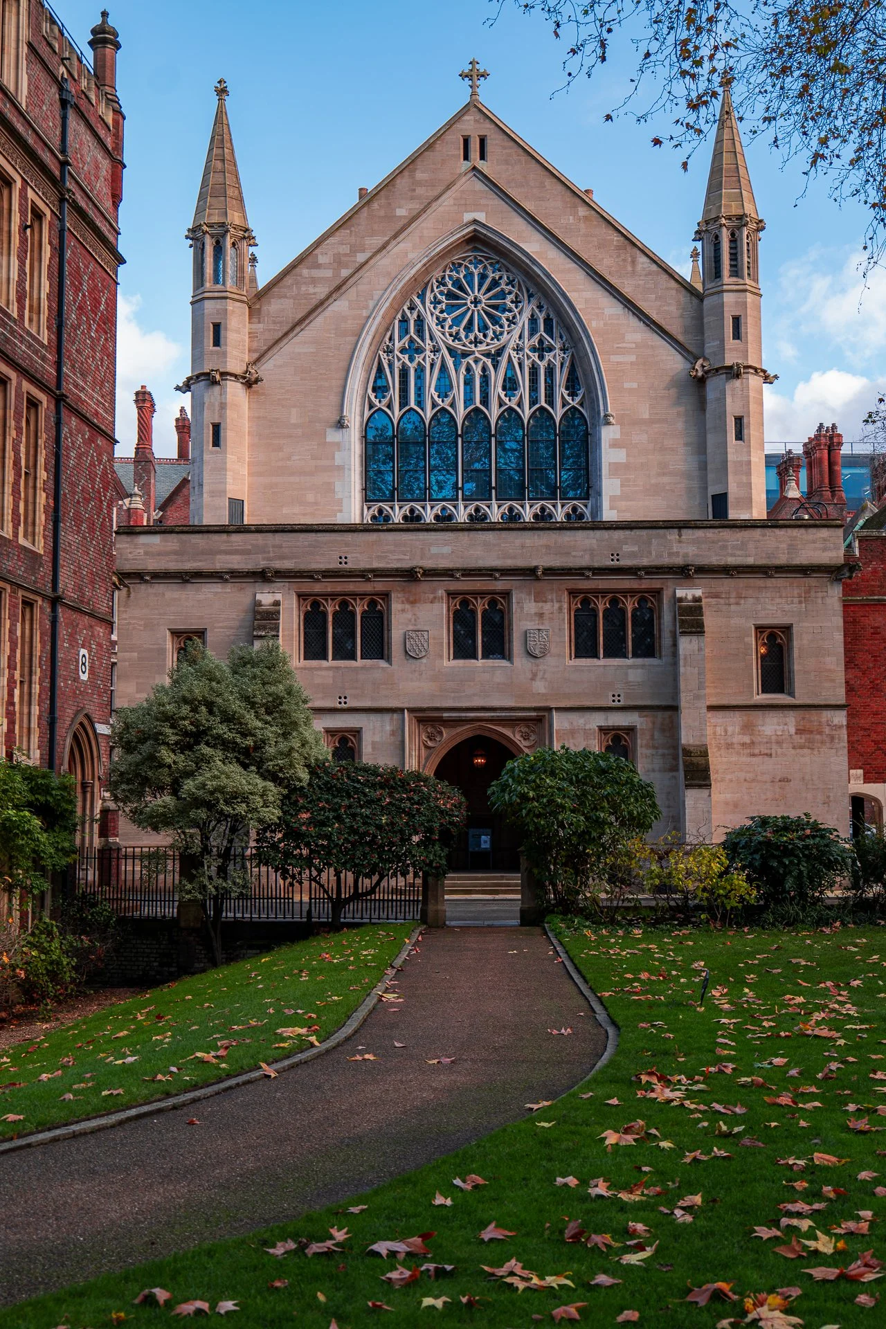Gothic-style building with pointed arches and ornate windows, surrounded by a winding path and greenery, under a blue sky.