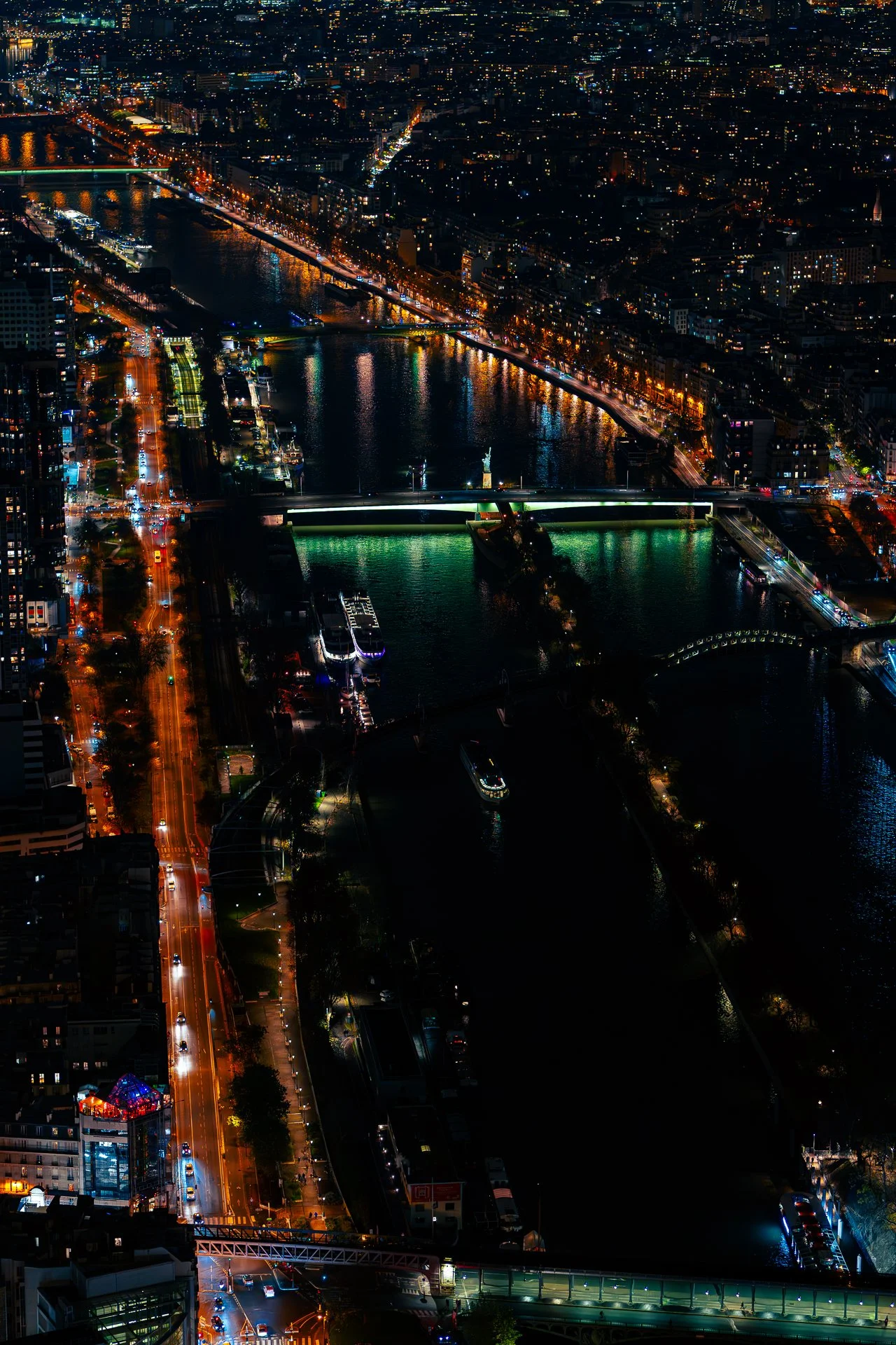 Aerial night view of a city with illuminated streets and bridges crossing a river.