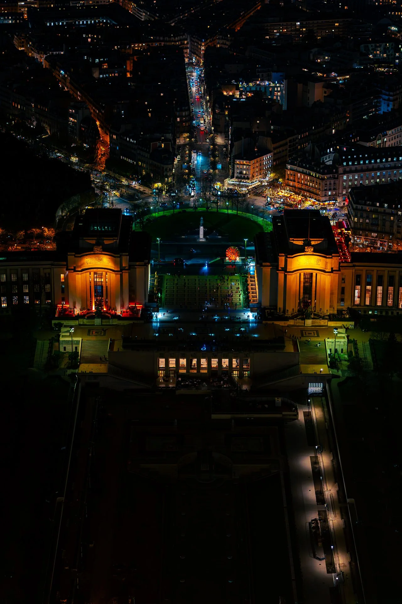 Night aerial view of Paris cityscape with illuminated buildings and streets, showcasing iconic structures and urban layout.
