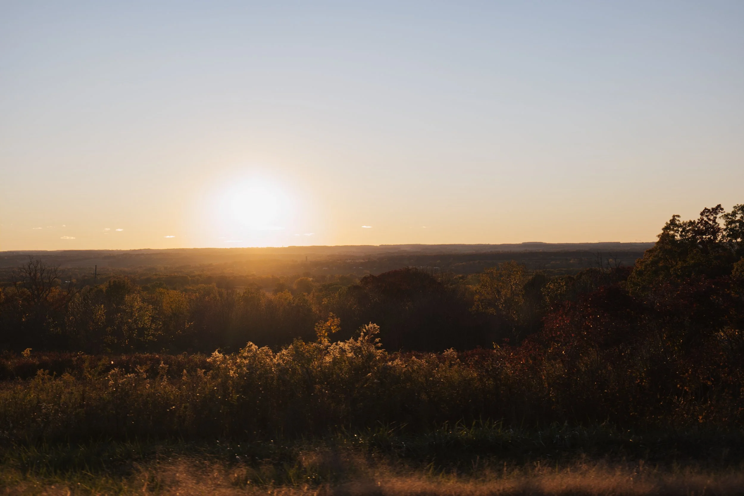 Scenic sunset over a field with trees and distant hills
