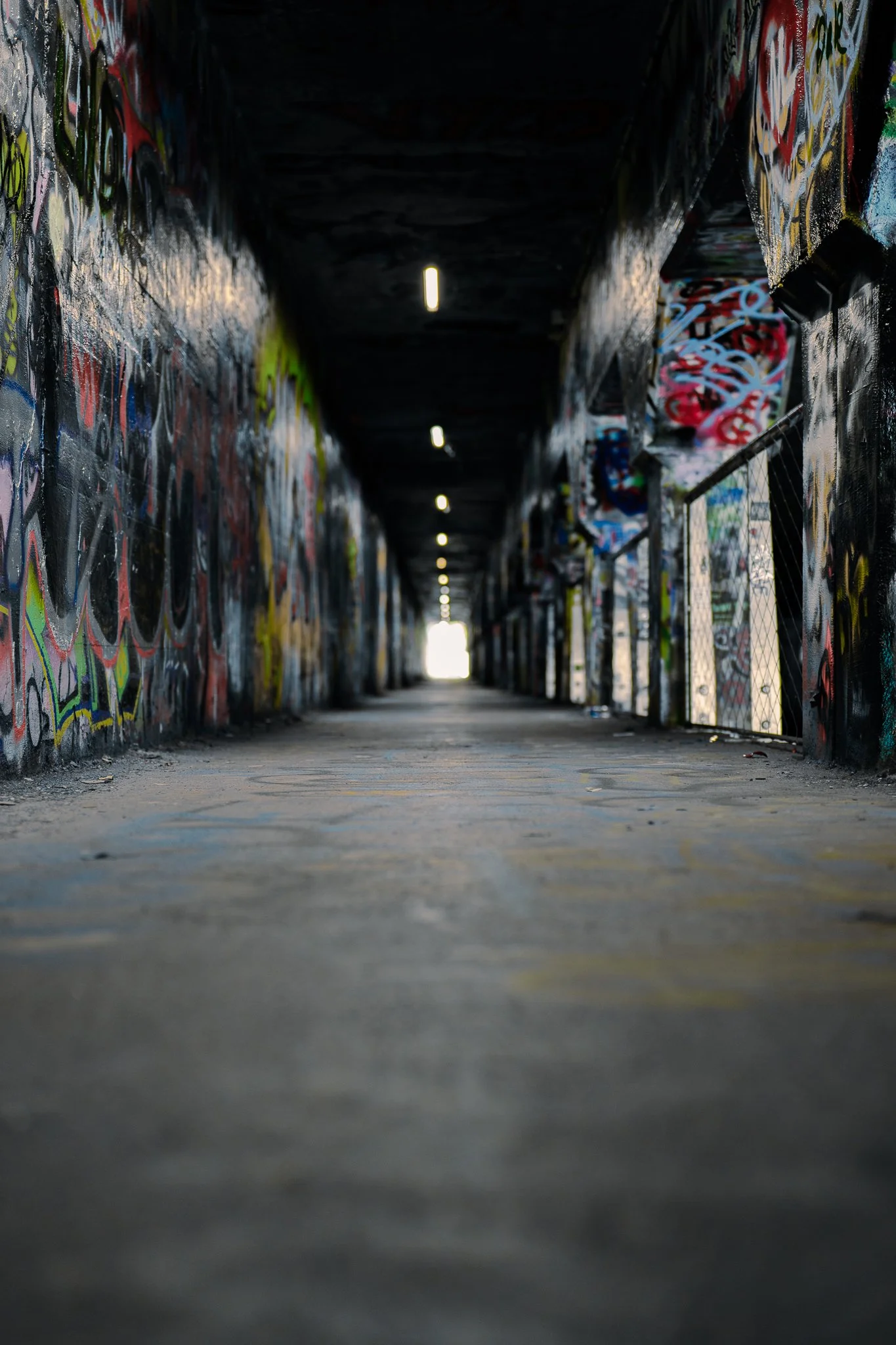 Graffiti-covered tunnel with overhead lights