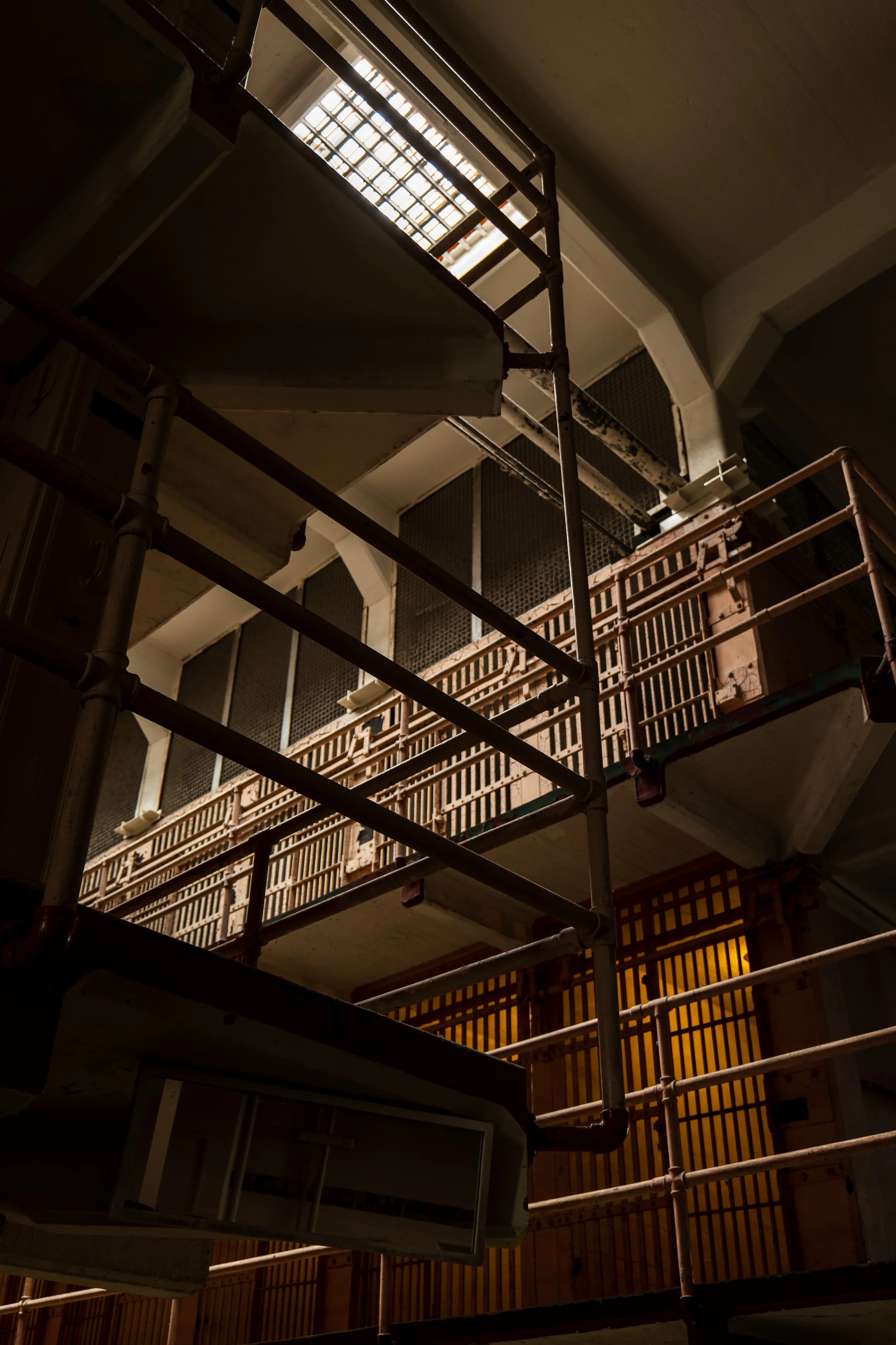 Interior view of a prison with metal railings and barred doors.