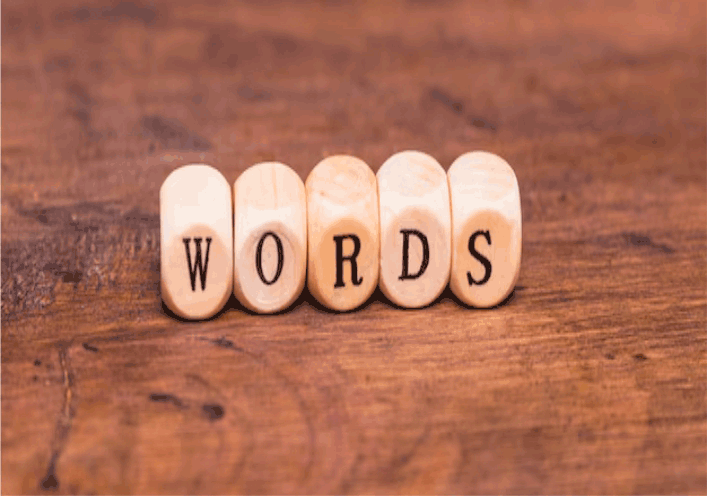 Wooden blocks spelling out the word 'WORDS' on a wooden surface.