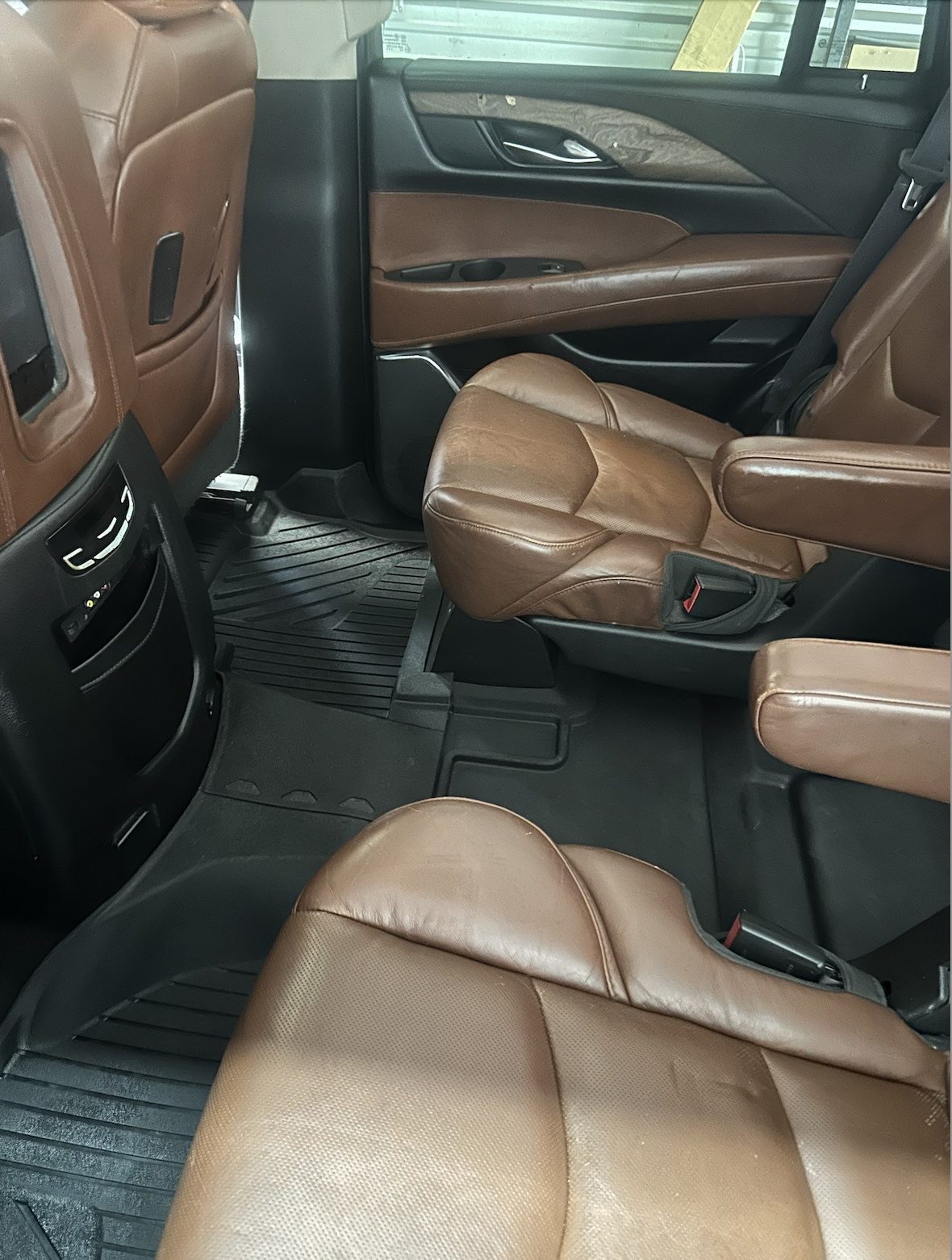 Interior of a vehicle showing brown leather seats and floor mats.