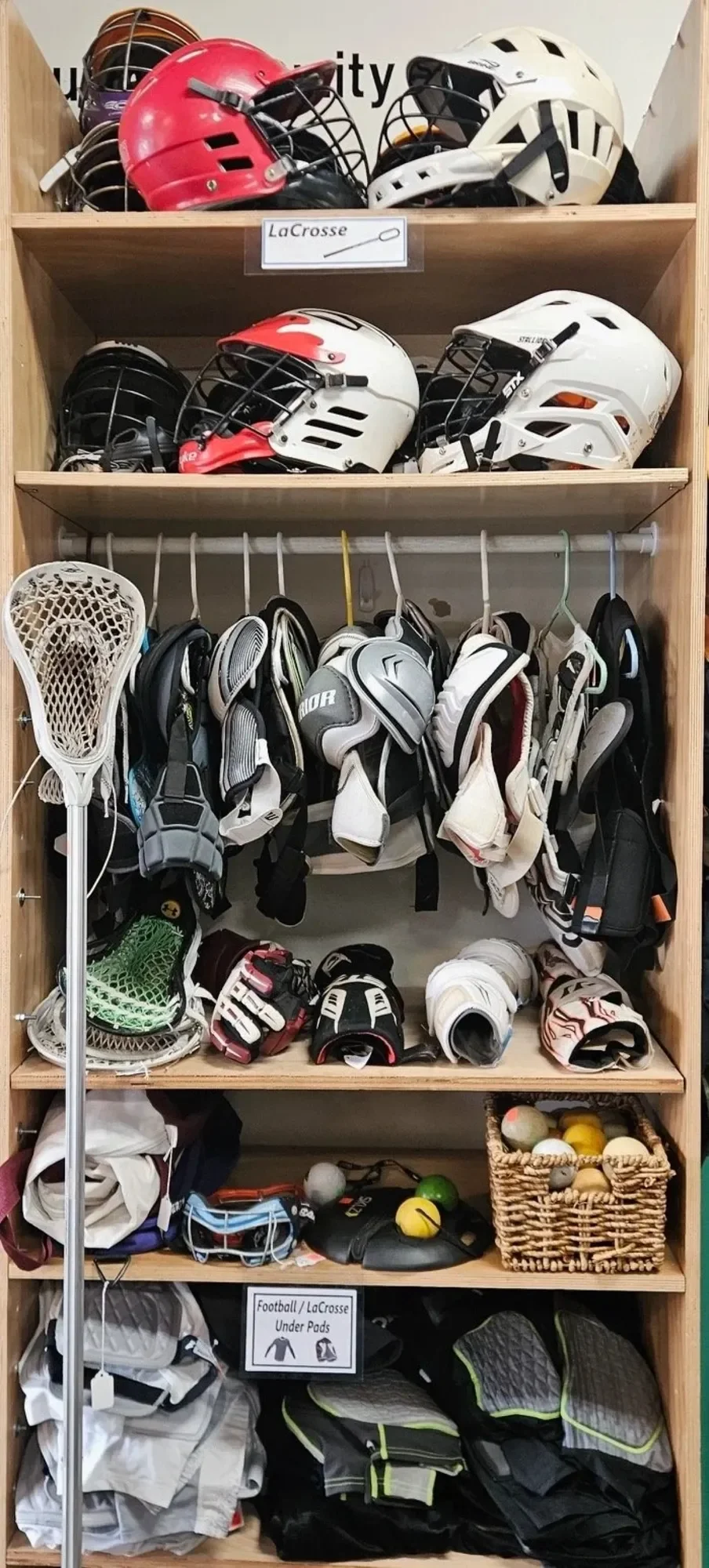 A wooden shelf with hockey equipment, including helmets, gloves, pads, and balls.