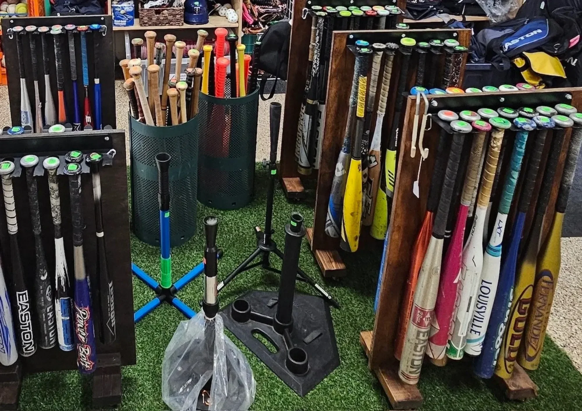 Display of baseball and softball bats stored on wooden racks at a sporting goods store.