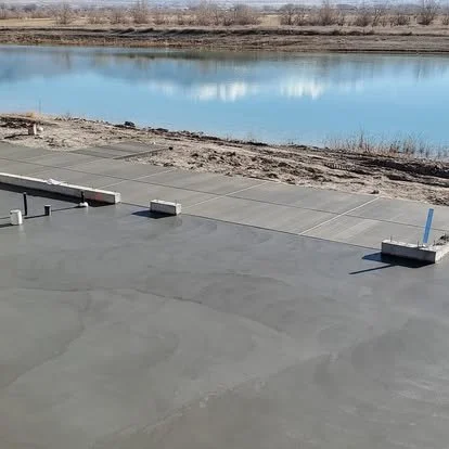 Concrete surface near a water body with some small barriers and marking poles