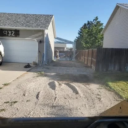 Driveway extension area before concrete installation, showing the gravel base and side-yard layout ready for prep work.