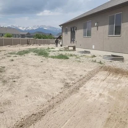 Backyard area before concrete installation, showing the open dirt space and layout area beside the home.