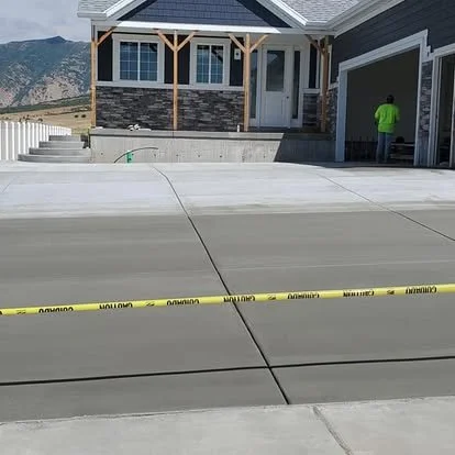 Newly finished concrete driveway and garage approach with crisp control joints and a clean curbside finish.