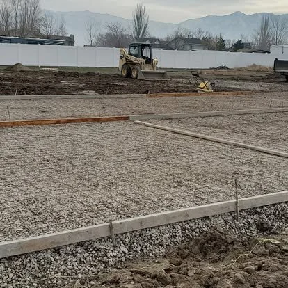Concrete project preparation with grading, gravel base, and forms being set for a large outdoor concrete area.