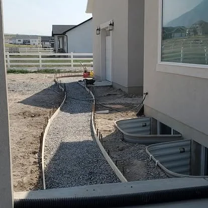 Walkway preparation with forms and compacted gravel base set along the side of the home.