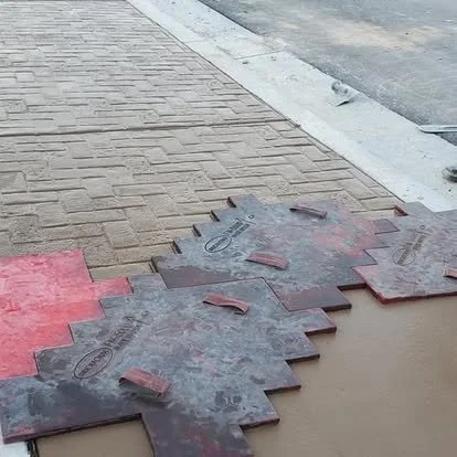 Decorative concrete stamping in progress using patterned mats to create a brick-style texture.