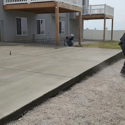 Finished backyard concrete patio with clean control joints, smooth edges, and a large usable area under the deck.