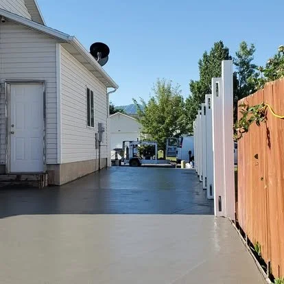Finished side-yard concrete pad with clean edges, smooth finish, and access through the fence gate.