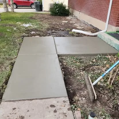 Finished concrete walkway connecting the yard and side entry area with clean edges and a smooth finish.