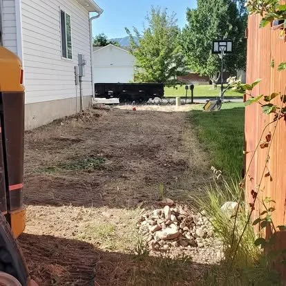 Side-yard area before concrete installation, showing the cleared dirt space and layout for a future pad or walkway.