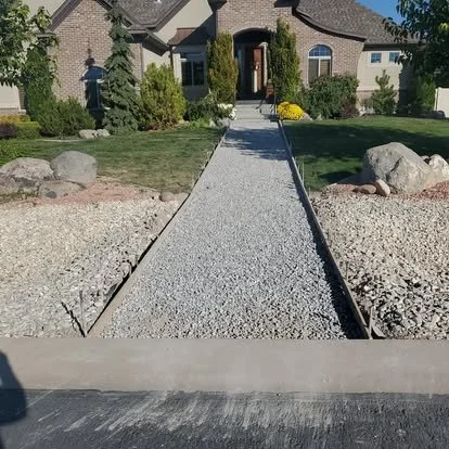 Front walkway before concrete installation, showing the gravel base and straight path layout through the landscaping.