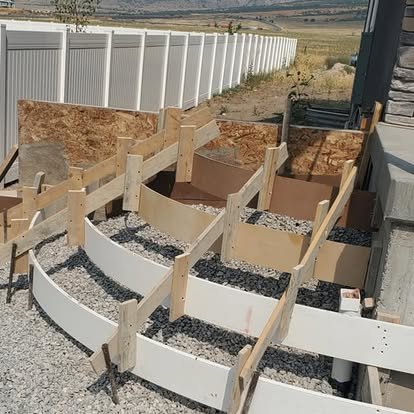 Concrete step project in progress with wood forms, gravel base, and curved stair layout ready for installation.