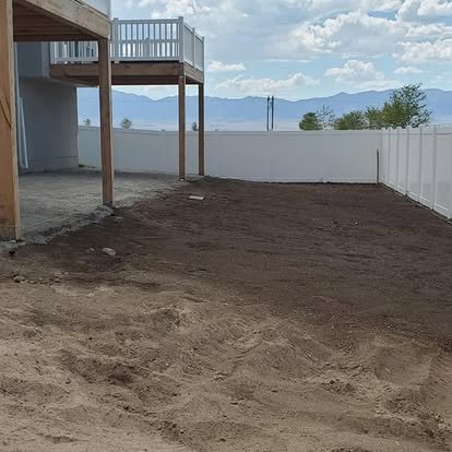 Backyard patio area before concrete installation, showing the cleared dirt space and layout area beneath the deck.
