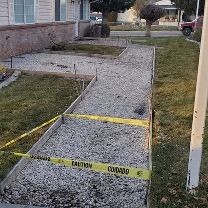 Front walkway preparation with gravel base, forms, and caution tape before the new concrete pour.