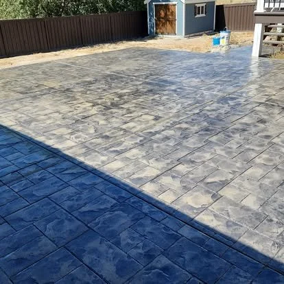 Concrete patio with decorative stamped pattern in an outdoor backyard.