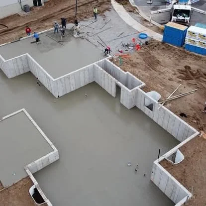 Aerial view of a large concrete foundation pour with forms, foundation walls, and crew members working on-site.