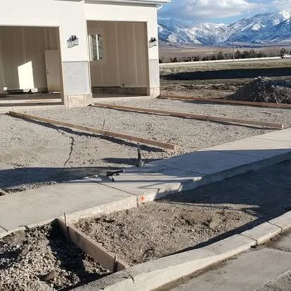 Concrete driveway preparation with forms, gravel base, and curb area ready for the next stage of installation.