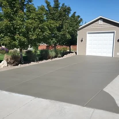 Fresh concrete driveway leading to a detached garage, finished with clean edges and a smooth surface.