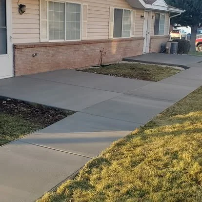Finished front concrete walkway with clean control joints, smooth finish, and a neat transition from the driveway to the home.