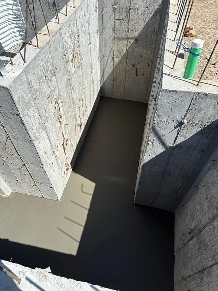 Concrete foundation and basement slab work with poured walls, smooth floor finish, and structural openings.