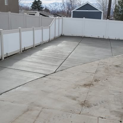 Finished concrete RV pad or side-yard parking area with clean control joints, smooth finish, and a neat layout along the fence.