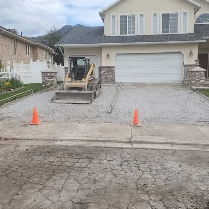 Driveway replacement in progress with the old surface removed and the gravel base being prepared for new concrete.