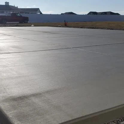 Large finished concrete patio or outdoor pad with a smooth surface, clean control joints, and a bright, polished appearance.