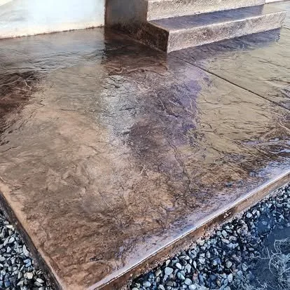 Finished stained concrete patio with a glossy sealed surface, textured detail, and clean step transition.