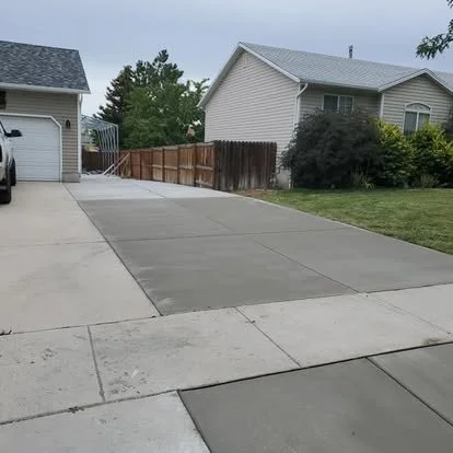 Finished concrete driveway extension and side parking area with clean joints, smooth finish, and extra usable space beside the home.