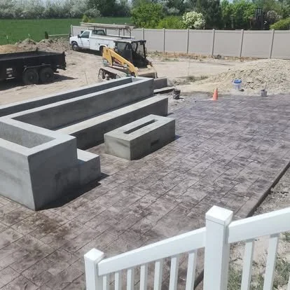 Finished stamped concrete patio with a decorative pattern, outdoor fire pit area, and clean surrounding concrete work.