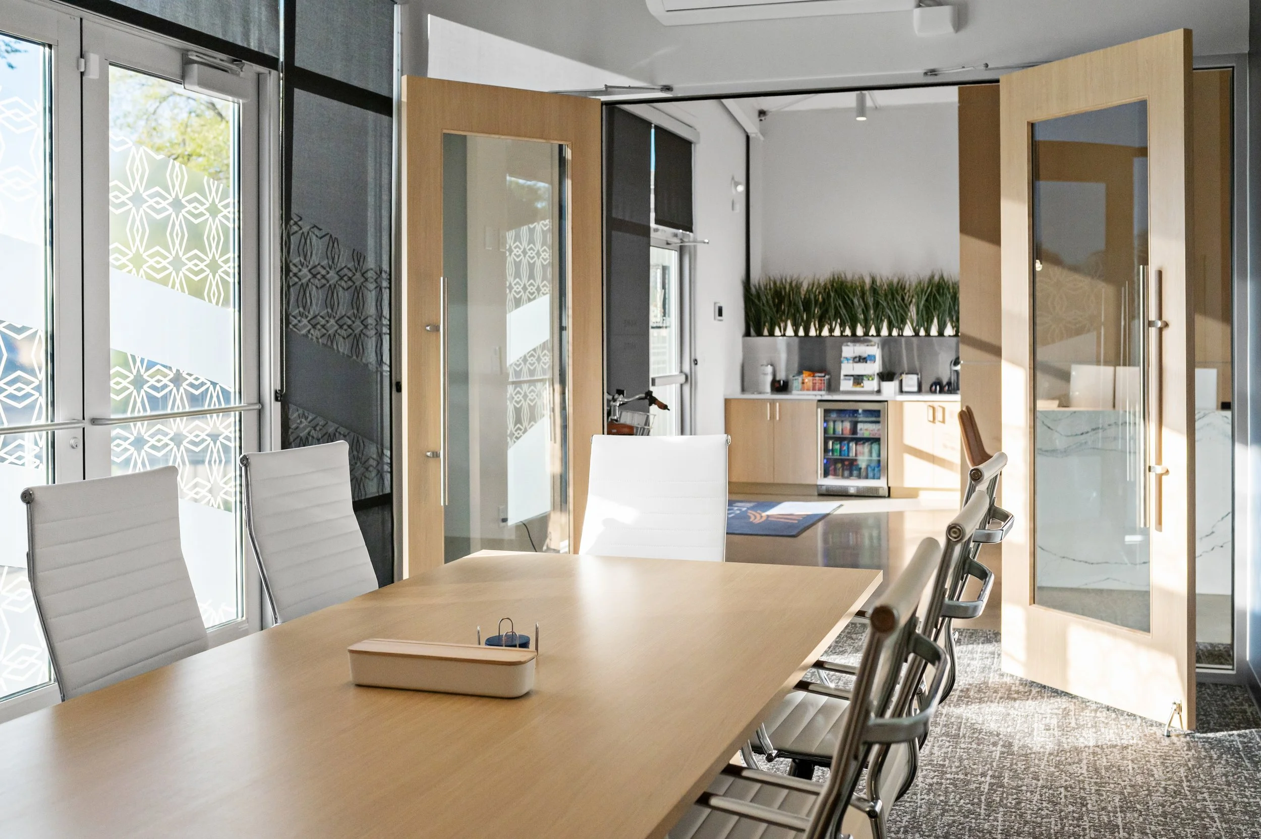 Western Insurance meeting room with white chairs around a light wood conference table and glass doors