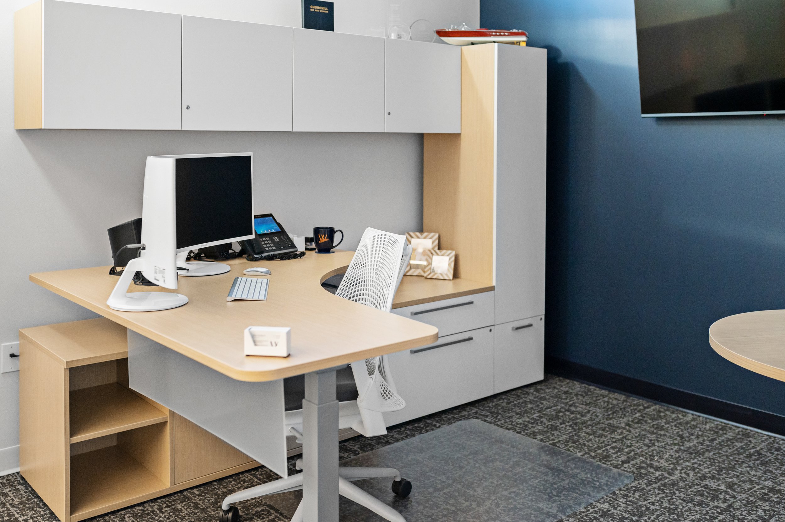 Office workspace with a desk, computer monitor, chair, and wall-mounted cabinets