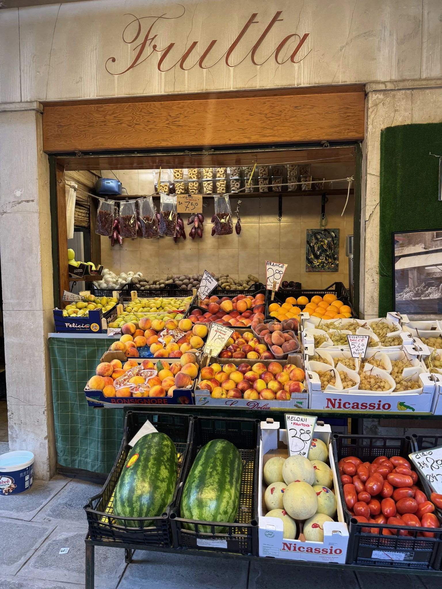 A fruit stand piled high with fresh, vibrant produce on a side street in Venice, Italy.