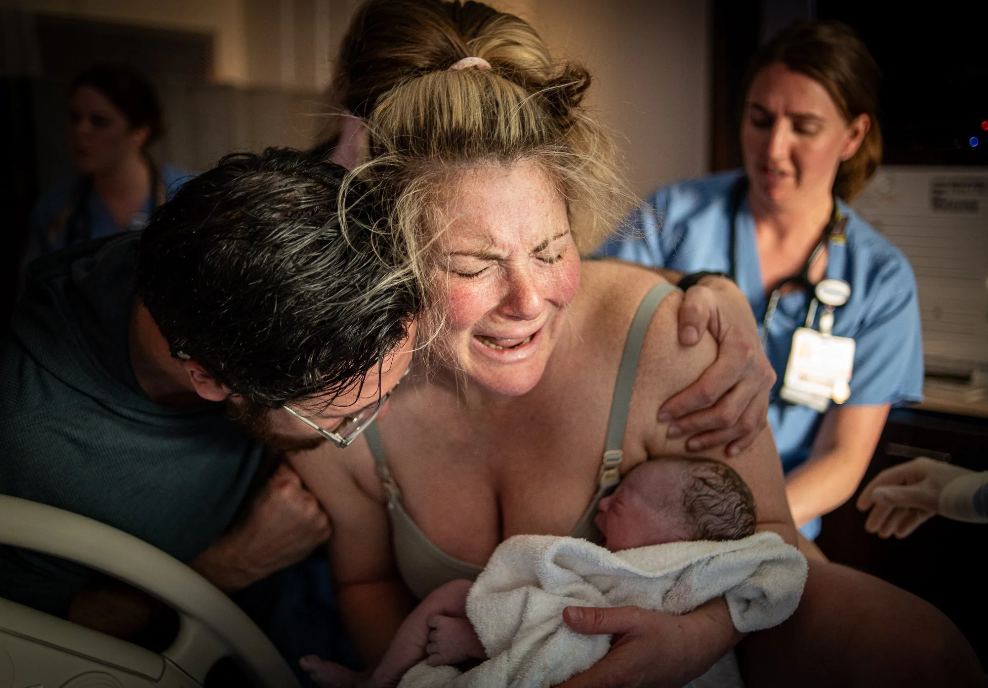 A woman giving birth with medical staff assisting in a hospital room.
