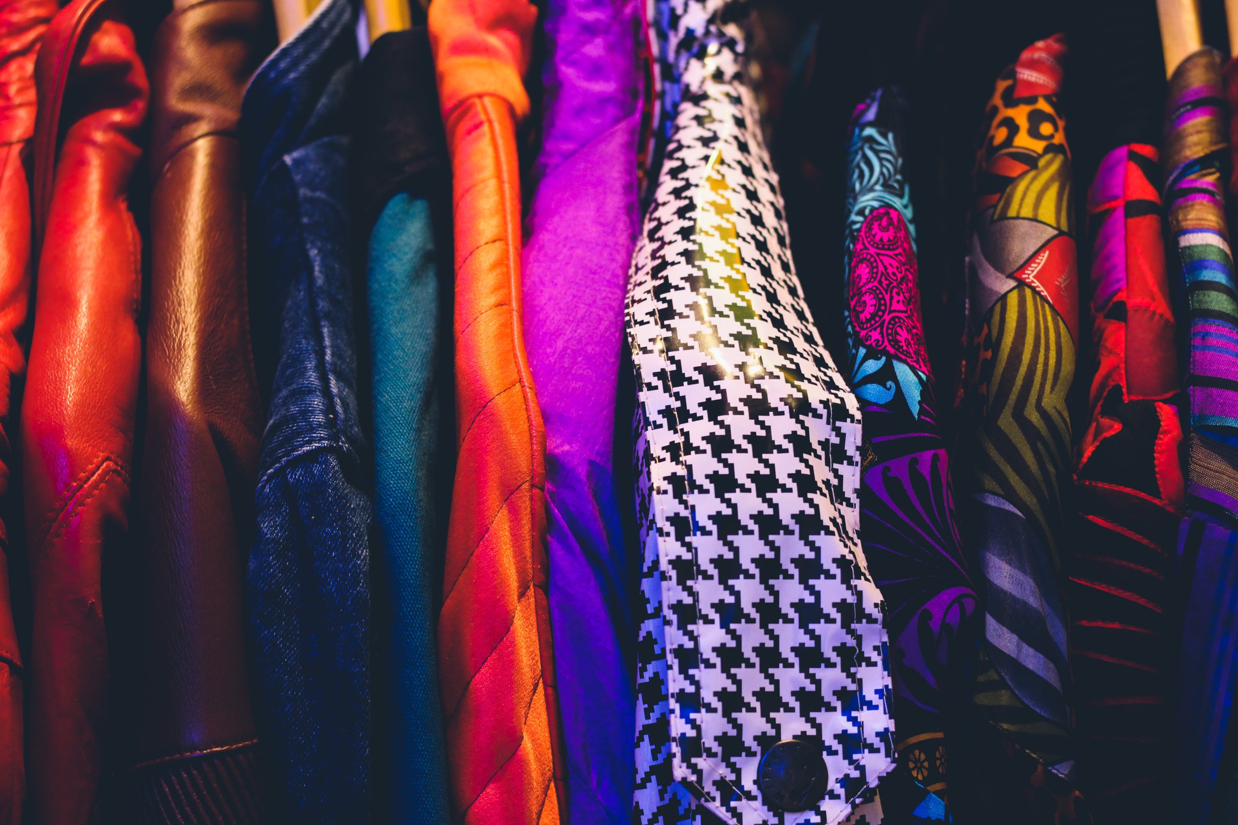 A row of colorful jackets hanging on a rack, with a variety of patterns and textures.