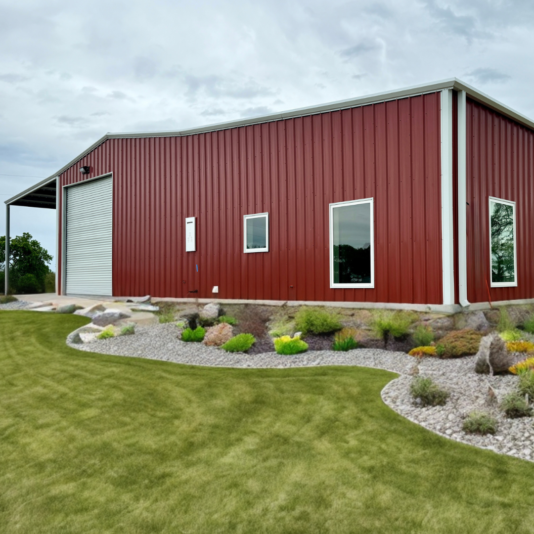 Red metal building / Barndominiumwith large roll  door, white vinyl frame residential windows. Red metal PBR panel walls and Polar White trim and gutters.