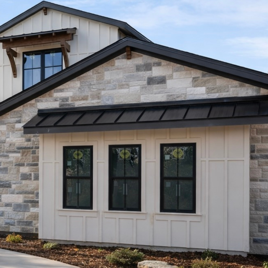 Exterior view of a luxury custom home hill country modern with black framed Pella windows, board and batten siding, limestone exterior, standing seam roof panels and black shingles.